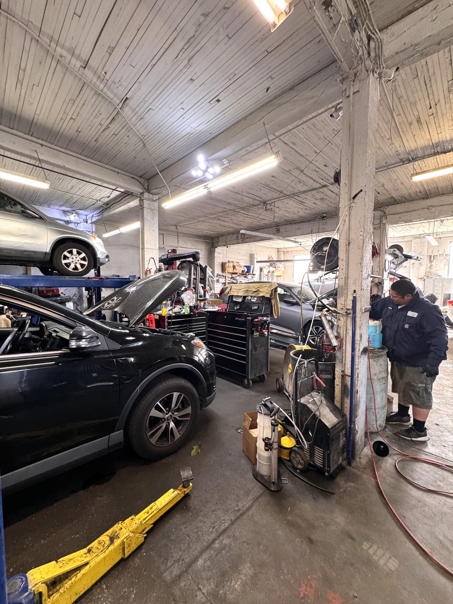 Wide view of the shop floor with multiple cars and technicians working