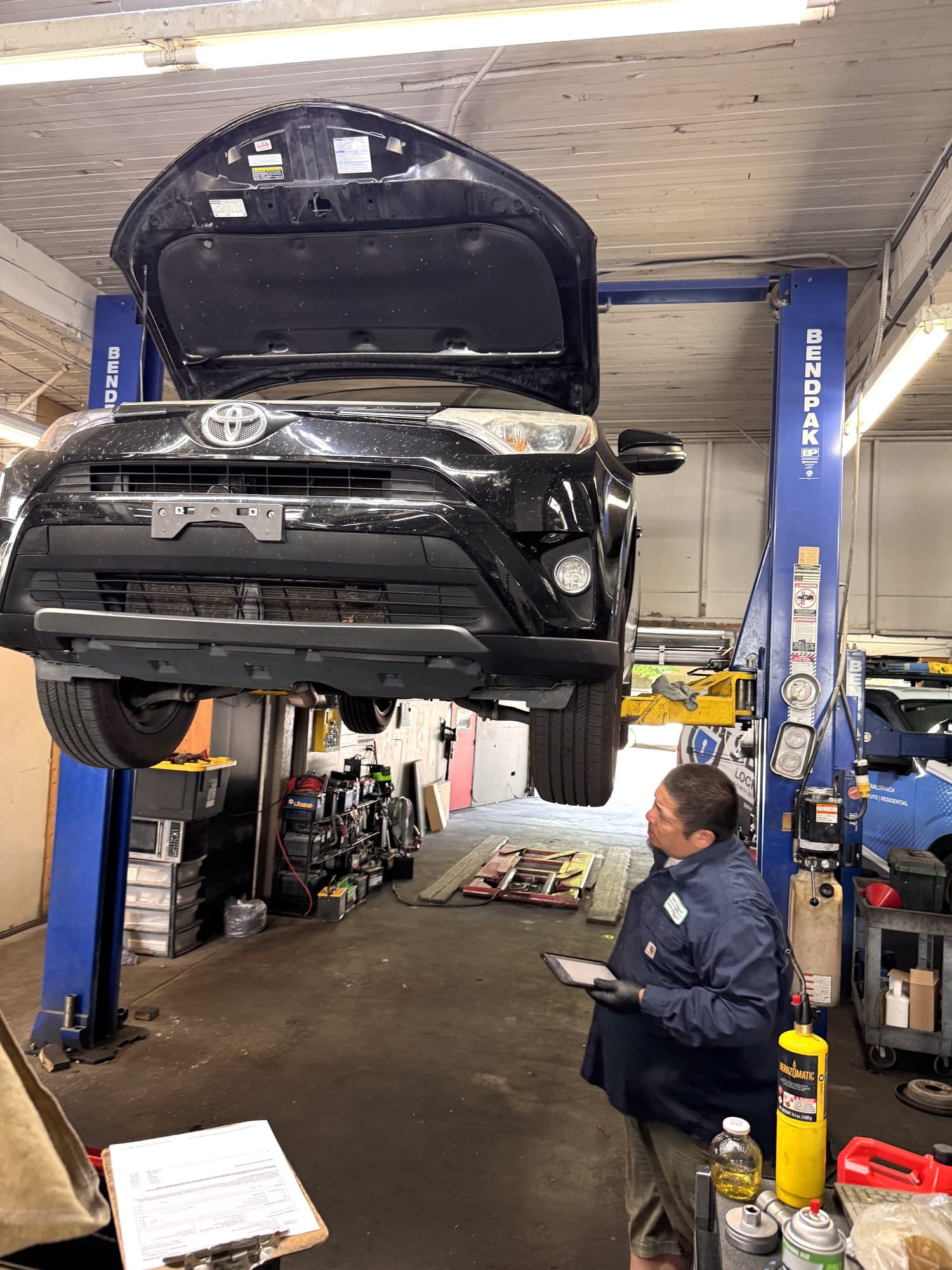 Technician with tablet inspecting a RAV4 raised on the BendPak lift